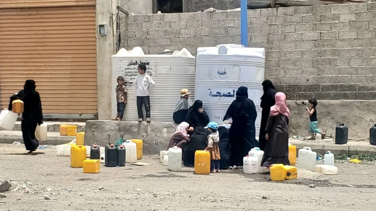 صورة لنساء يقفن بطوابير لتعبئة المياه بمشهد يبرز معاناتهن وعدم المساواة في التوزيع
