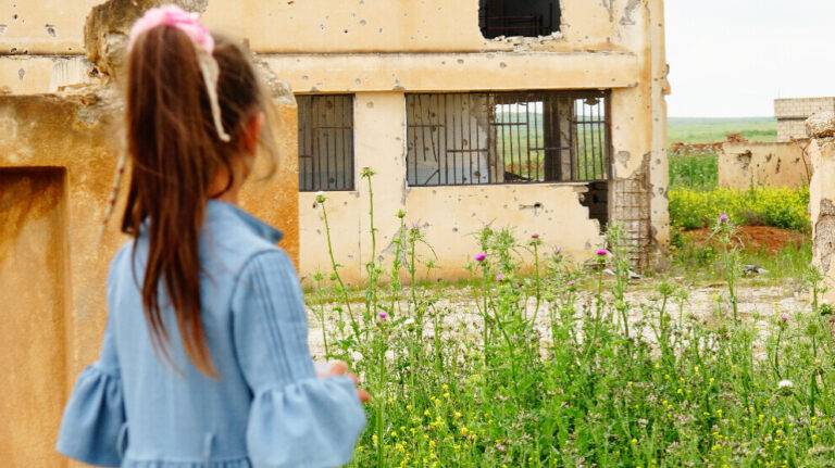 طفلة سورية تنظر إلى قريتها تل الورد بعد عودتها مع أسرتها