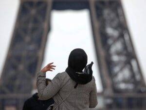 صورة امرأة محجبة تقف أمام برج إيفل في العاصمة الفرنسية باريس