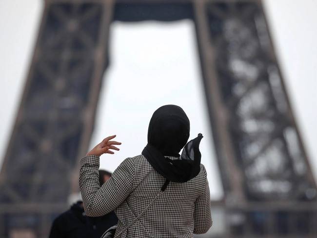 صورة امرأة محجبة تقف أمام برج إيفل في العاصمة الفرنسية باريس